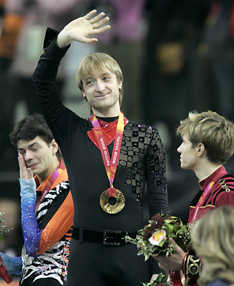 Gold Medal winner Evgeni Plushenko from Russia waves to the crowd as silver medal winner Stephane Lambiel (L) from Switzerland wipes away his tears and bronze medal winner Jeffrey Buttle from Canada looks on, after the men's figure skating at the Torino 2006 Winter Olympic Games in Turin, Italy, February 16, 2006. [Reuters]