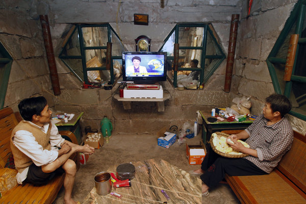 A Southwest China couple, who made a cliff-side cave their home 17 years ago, watch TV in their living room on July 11, 2011. The power is provided by the municipality of Chongqing to the remote cliff near the outskirts of the city.[ Couple's 17 years of seclusion at cave