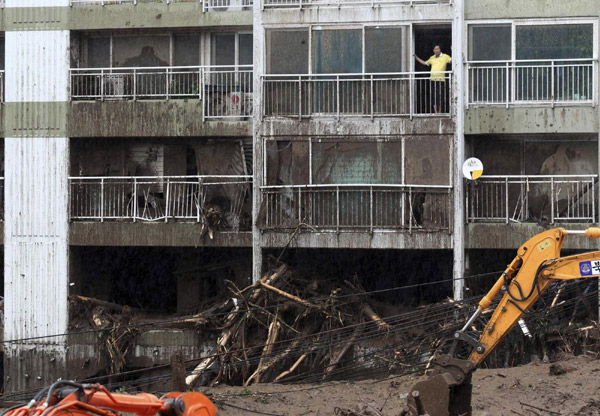 A resident in an apartment looks at debris after a landslide caused by a heavy rainfall in Seoul July 27, 2011. Wild weather has battered the peninsula since late Tuesday, causing widespread flooding and transport delays, while the share price of insurers fell on fears that damage costs would run into millions of dollars. Rain sets off mudslide in South Korea