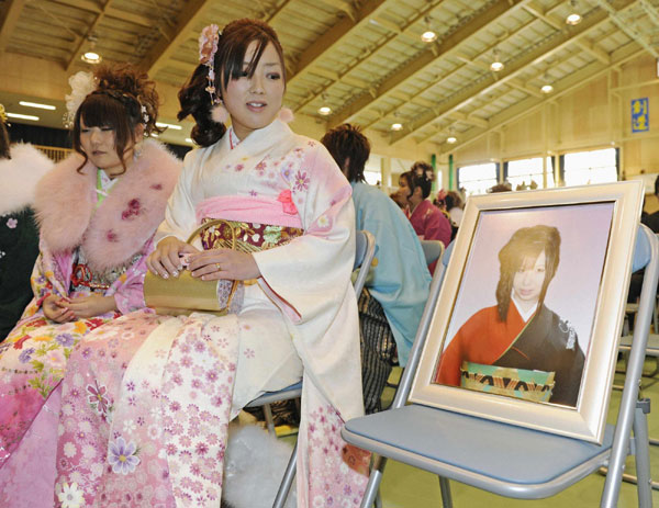 A portrait of a victim of the March 11, 2011 tsunami is seen beside a woman during a Coming of Age Day event in Iwate prefecture, Jan 8, 2012. 'Coming of Age Day' with record low number of new adults