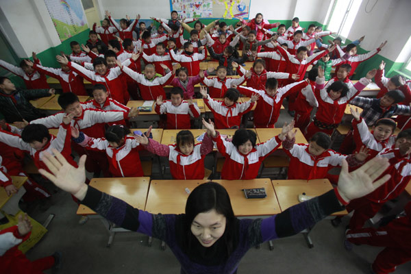 A teacher leads a class of pupils doing their exercises between classes in a classroom instead of outdoors, at a primary school in Jinan city, Capital of East China's Shandong province on Jan 14 Heavy fog forces kids to stay in classroom for exercise