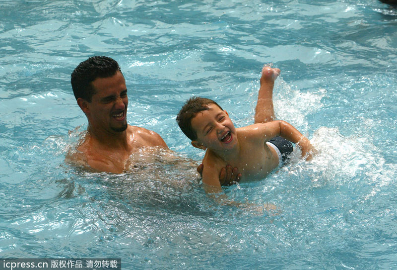 An Iraqi father and his son enjoy splashing in a swimming pool in the Salhiyeh district of Baghdad, on June 6, 2008. Public sports in post-war Iraq