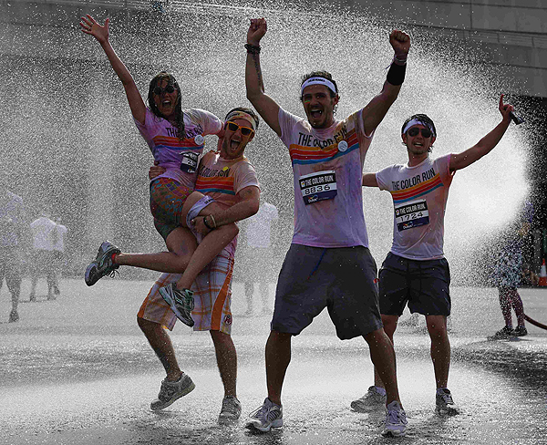 Runners pose for a photograph as they are sprayed with cold water after finishing The Color Run outside Wembley Stadium in London, July 14, 2013. The Color Run is a five kilometre, un-timed race, held in cities across the US and also worldwide, with the aim of promoting healthy living, and the organizers choose a charity to benefit in each of the cities the run visits. Participants are doused from head to toe in different colours at each kilometre. Color Run in London promotes healthy living