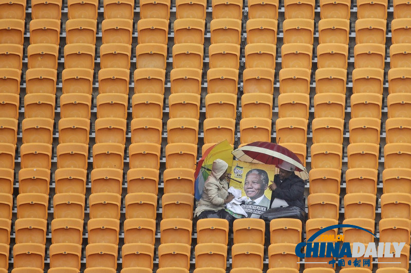 曼德拉追悼會現(xiàn)場:情侶為偉人海報打傘