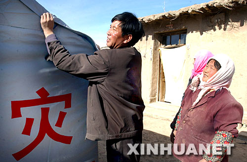 2003年11月12日，甘肅山丹縣李橋鄉劉莊村黨支部書記王升（左）在該村七社村民王金秀（右）家檢查抗震救災帳篷密封情況。2003年10月25日，甘肅山丹縣發生6.1級地震后，該縣廣大黨員干部一直奮戰在抗震救災第一線。 新華社發 