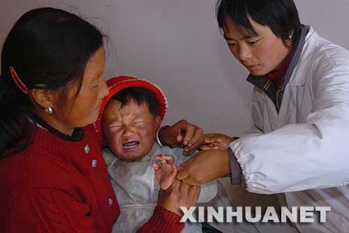2004年11月17日，麗江市玉龍納西族自治縣長水村黨員寸秀英（右）在給村里的納西族孩子和梅看病。云南省麗江市玉龍納西族自治縣長水村黨支部大力加強基層黨組織的建設，充分發揮黨員在經濟發展中的作用，使該村經濟發展迅速，群眾生活明顯改善。 新華社發 