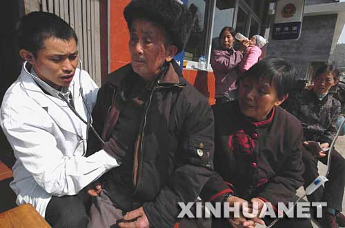 2007年3月20日，貴州省萬山特區黃道侗族鄉臨湘村村醫、共產黨員楊林（左一）在為村民診病。在貴州和湖南兩省交界的山村里，他15年如一日地牽掛著百姓的健康，被當地村民親切地稱為“健康守護神”。 新華社發 