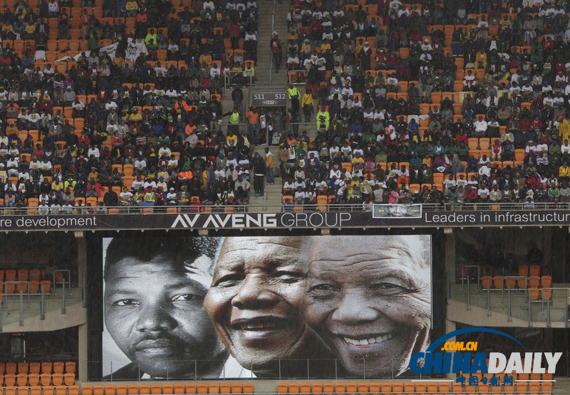 曼德拉追悼會(huì)現(xiàn)場(chǎng)：情侶為偉人海報(bào)打傘