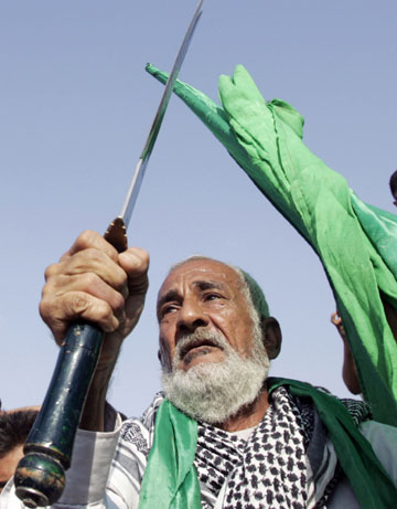 An elderly man holds a sword as residents celebrate in reaction to the verdict against former Iraqi leader Saddam Hussein in Baghdad's Sadr city, November 5, 2006. A shaken but defiant Saddam was sentenced to hang on Sunday for crimes against humanity, sparking joy for Shi'ites he oppressed and resentment among his fellow Sunnis across Iraq's violent sectarian divide.