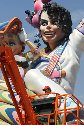 A craftsman operates a crane past a giant sculpture of singer Michael Jackson during the final preparations before the