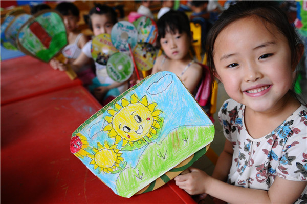 Kids show off fans made of recycled paper in a kindergarten in Liaocheng city, Shandong province on June 17, 2013. National Low Carbon Day goes green