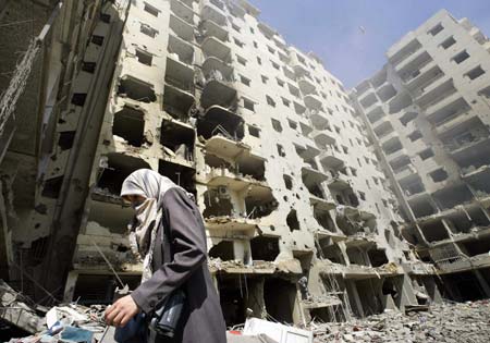 A Lebanese woman walks near the rubble of a building, which was destroyed in an Israeli air raid on Sunday, in Beirut's southern suburbs August 14, 2006. Guns fell silent across southern Lebanon on Monday after a U.N.-brokered truce went into effect to end five weeks of fighting between Israel and Hizbollah that killed more than 1,250 people and wounded thousands.