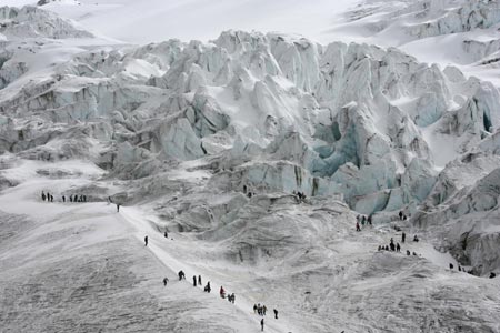 People walk along the slopes of the Cayambe volcano during the Ruta del Hielo (Ice Route) competition, 45 kilometres north of Quito, August 27, 2006. Participants carry blocks of glacial ice on their backs down the 5,790 meter-high volcano to the town. The annual competition evolved from the tradition of ice harvesting to make ice cream, a practice that died with the advent of electric ice-makers.