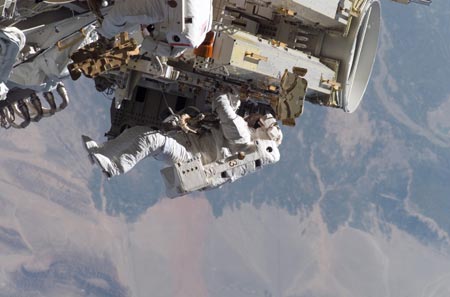Astronaut Heidemarie Stefanyshyn-Piper releases the restraints on the forward Solar Array Blanket Box (SABB) during a spacewalk with astronaut Joseph Tanner (partially visible at top edge of frame) September 12, 2006.