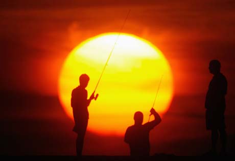 Cuban fishermen stand during sunset at Havana's Malecon sea front, October 13, 2006.