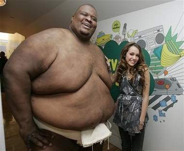 Actress Miley Cyrus appears back stage with sumo wrestler Manny Yarbrough during MTV's 'Total Request Live' show at the MTV Times Square Studios, Monday, Oct. 23, 2006, in New York