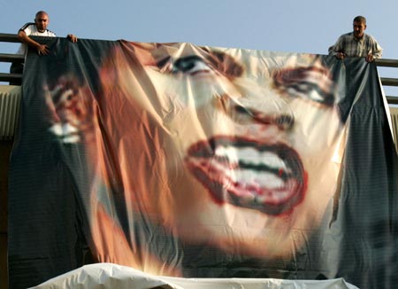 Lebanese protesters unfold a poster of U.S. Secretary of State Condoleezza Rice during a protest in Beirut, July 30, 2006 after an Israeli air raid on Qana, killed more than 54 people, 37 of them children, in south Lebanon, July 30, 2006.