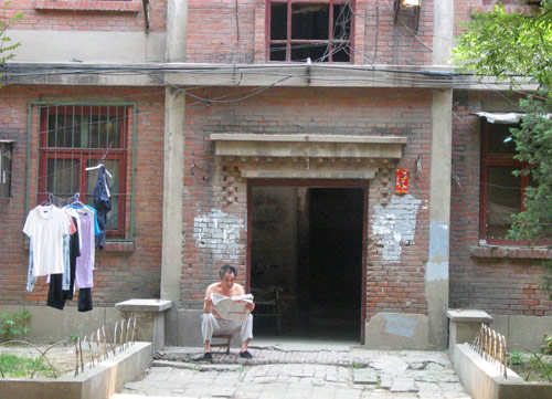 A Chinese man reads newspaper in Juixiaqiao Sub-district in Beijing, June 9, 2007. Local government in Jiuxianqiao and the real estate developer jointly organize the vote on Saturday to see if majority residents of over 5000 families accept the new compensation policy after failed attempts to reach an agreement through other ways. Both notary officials and supervisors are invited to monitor the vote that runs from 9 a.m. to 9 p.m. at six ballot booths. [Sun Yuqing/www.szjzcy.com]
