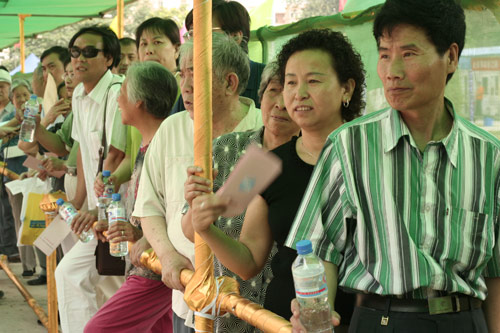 Residents wait to cast their votes on the demolishment and reconstruction of old buildings in Juixiaqiao Sub-district in Beijing, June 9, 2007. Local government and the real estate developer jointly organize the vote on Saturday to see if majority residents of over 5000 families accept the new compensation policy after failed attempts to reach an agreement through other ways. Both notary officials and supervisors are invited to monitor the vote that runs from 9 a.m. to 9 p.m. at six ballot booths. [Sun Yuqing/www.szjzcy.com]