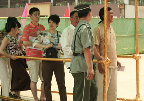 A security man talks with residents at the venue for a vote on demolishment and reconstruction of old buildings in Juixiaqiao Sub-district in Beijing, June 9, 2007. Local government and the real estate developer jointly organize the vote on Saturday to see if majority residents of over 5000 families accept the new compensation policy after failed attempts to reach an agreement through other ways. Both notary officials and supervisors are invited to monitor the vote that runs from 9 a.m. to 9 p.m. at six ballot booths. [Sun Yuqing/www.szjzcy.com]