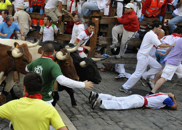Runners sprint and fall next to Victoriano del Rio fighting bulls at Telefonica corner during the sixth running of the bulls at the San Fermin festival in Pamplona July 12, 2011. Bulls run at San Fermin festival