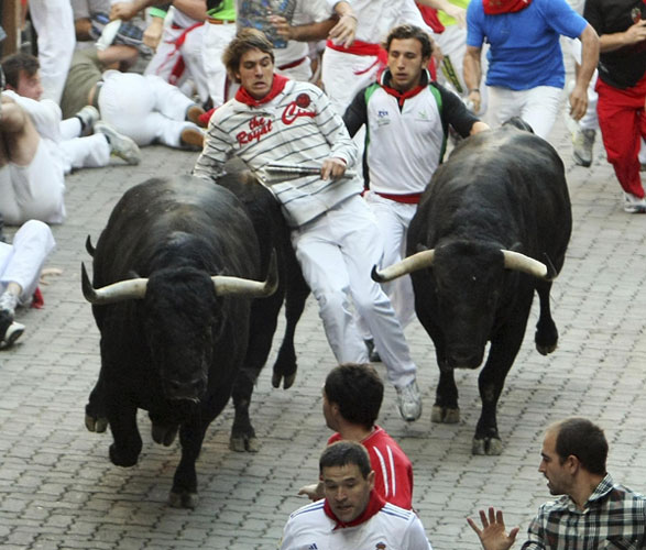 A runner is caught in between two Victoriano del Rio fighting bulls at the entrance to the bullring during the sixth running of the bulls at the San Fermin festival in Pamplona July 12, 2011. Bulls run at San Fermin festival