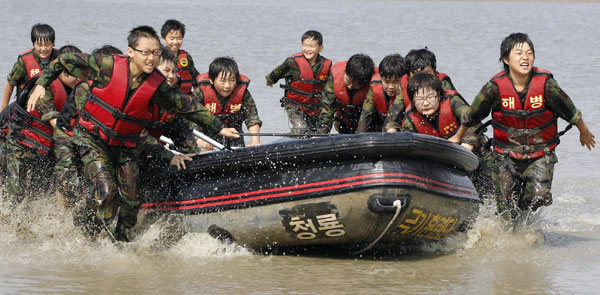 Elementary school students carry a rubber boat as they participate in a summer military camp for civilians at the Cheongryong Self-denial Training Camp run by retired marines in Ansan, about 40 km (25 miles) southwest of Seoul, July 21, 2011. Summer military camp for South Korean kids