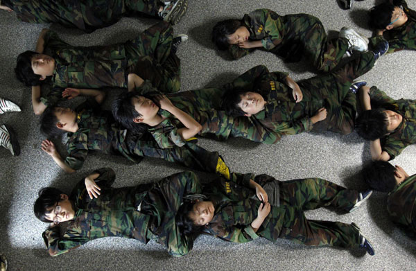 Elementary school students take a nap on a floor after a morning exercise as they participate in a summer military camp for civilians at the Cheongryong Self-denial Training Camp run by retired marines in Ansan, about 40 km (25 miles) southwest of Seoul, July 21, 2011. Summer military camp for South Korean kids