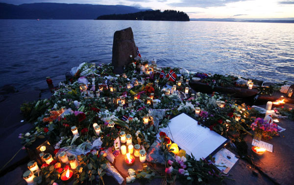 Flowers and candles are seen at a temporary memorial site for the victims of the shooting spree and bomb attack in Norway, on the shore in front of Utoeya island, northwest of Oslo, July 26, 2011. Paying respect for the twin attack victims
