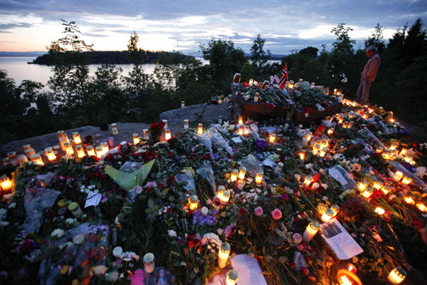 A man pays his respects to the victims of the shooting spree and bomb attack in Norway at a temporary memorial site on the shore in front of Utoeya island, northwest of Oslo, July 26, 2011.[ Paying respect for the twin attack victims