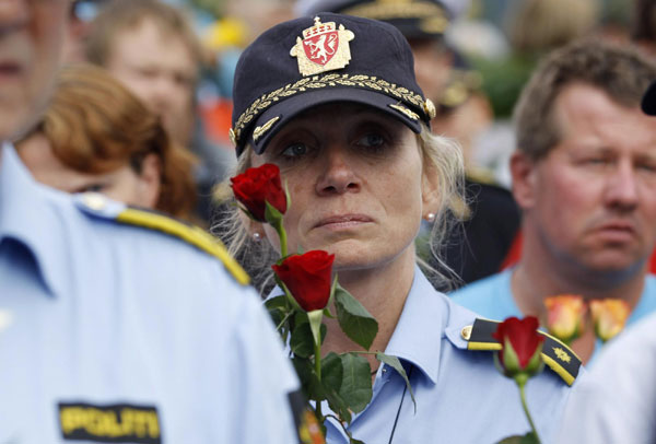 A police woman holds flowers as she takes part in a march near Utoeya island to pay their respects for the victims of the killing spree and bomb attack in Norway, in the village of Sundvollen, northwest of Oslo, July 26, 2011 Paying respect for the twin attack victims