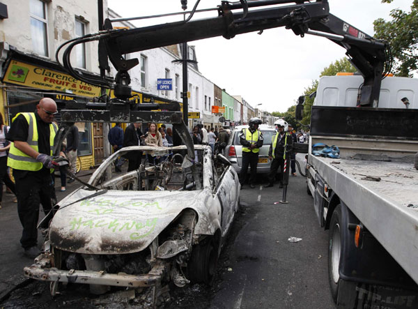 A council worker removes a destroyed vehicle, spray painted with the slogan 'Welcome to Hackney' in Hackney, north London August 9, 2011. London scarred after riots