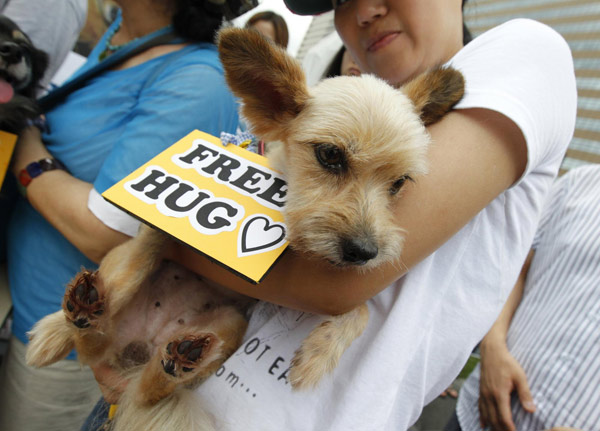 An animal rights activist holds a dog, which was abandoned before being adopted by its current owner, during a protest against the eating of dog meat on 'Malbok' in central Seoul Aug 13, 2011. Seoul activists: Dogs are friends, not food