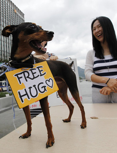 An animal rights activist smiles next to a dog, which was abandoned before being adopted by its current owner, during a protest against the eating of dog meat on 'Malbok' in central Seoul Aug 13, 2011. Seoul activists: Dogs are friends, not food