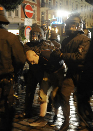 Police escort a demonstrator past the Rote Flora alternative cultural centre during clashes at the so-called street party 'Schanzenfest' in the Schanze district in Hamburg August 20, 2011. Demonstrators clash with police in Hamburg