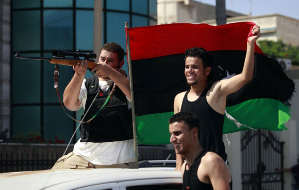 Libyan rebel fighters celebrate as they drive through Tripoli's Qarqarsh district August 22, 2011. Rebels seize Tripoli, inch toward victory
