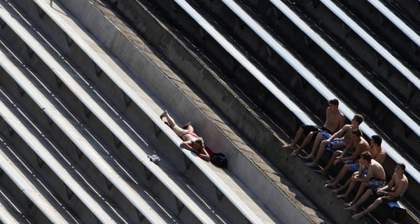 Men watch a woman sunbathing at a public swimming pool in Prague as temperatures hovered over 33 degrees Celsius (91.4 degrees Fahrenheit) August 23, 2011. People out for sunbath in Prague