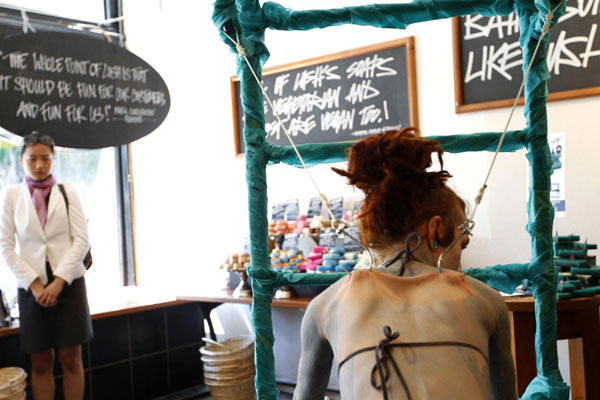 British performance artist Alice Newstead suspends from shark hooks pierced through her back at a cosmetic shop in San Francisco, California August 24, 2011.[ Hooked artist calls for shark protection