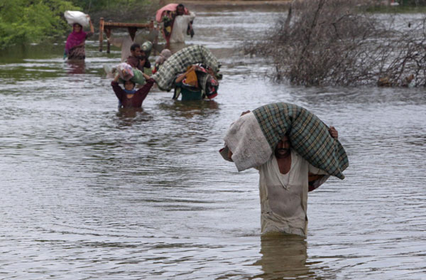 Villagers carry their belongings as they wade through flood waters in the town of Khoski, in Badin district of Pakistan's Sindh province Sept 13, 2011. Floods rattle Pakistan, 300,000 homeless