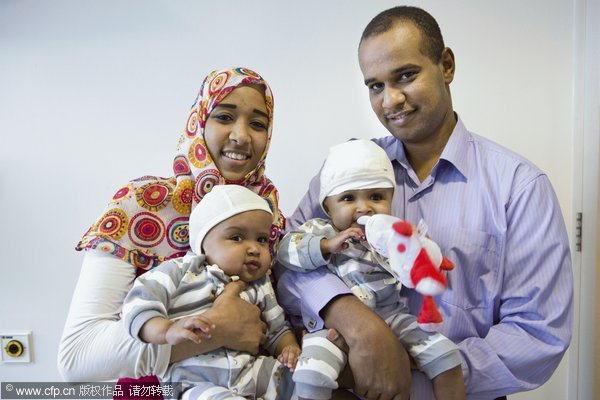 The twins, who were joined at the head, are held by their parents after four successful surgeries to separate them, Sept 15, 2011. Conjoined twin girls separated