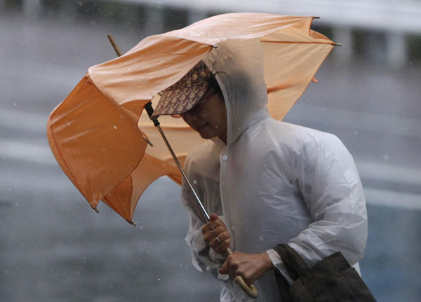 A passer-by struggles with strong winds and rain caused by Typhoon Roke in Tokyo September 21, 2011. Typhoon Roke lashes Japan, killing at least 6