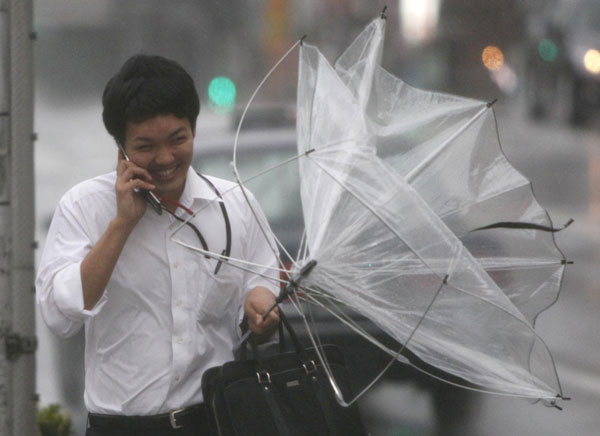 A passer-by struggles with strong winds and rain caused by Typhoon Roke in Tokyo September 21, 2011. Typhoon Roke lashes Japan, killing at least 6