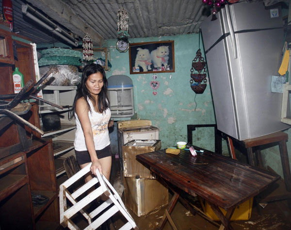 A resident cleans up her mud-filled house after flooding in Marikina City, Metro Manila Sept 28, 2011. After flood hits Metro Manila