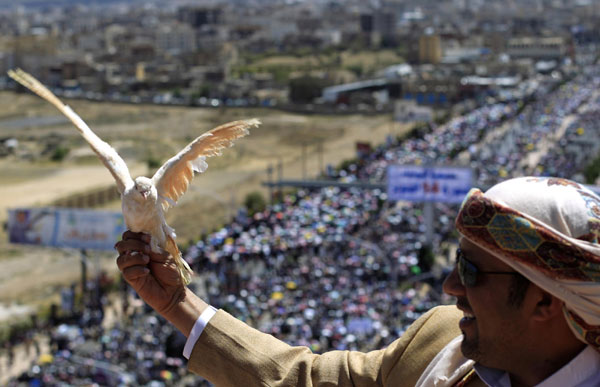 An anti-government protester holds a pigeon as he stands on the roof of a building overlooking thousands of fellow protesters attending a rally to demand the ouster of Yemen's President Ali Abdullah Saleh in Sanaa Oct 14, 2011. Protesters demand ouster of Yemen's president
