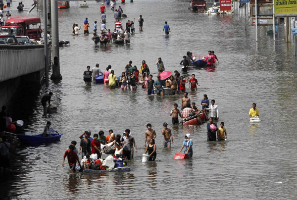 People push their belongings through floodwaters during an evacuation from a flooded area at Pathum Thani province, in Bangkok's suburbs, October 21, 2011. Floodwater forces evacuation in Bangkok's suburb