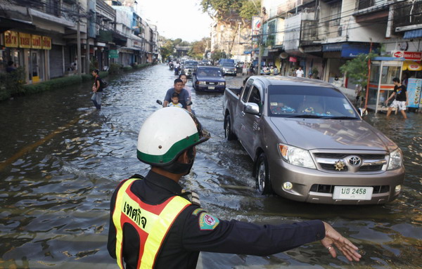 A Bangkok city policeman directs traffic as cars drive along a street flooded from the overflowing Chao Phraya river at Phranakhon district in Bangkok October 24, 2011. Bangkok on high alert with worst floods in 50-yrs