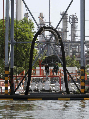 Workers stand in front of an oil refinery near the Chao Phraya river in Bangkok Oct 31, 2011. Thailand hopes flooded industrial estates back up