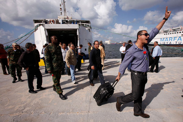 A man shouts as he disembarks from the first boat carrying travellers since Feb 2011 from Cyprus to Tripoli, at El Chaab sea port, in Tripoli, Nov 10, 2011. Tripoli sees first boat with travellers since Feb