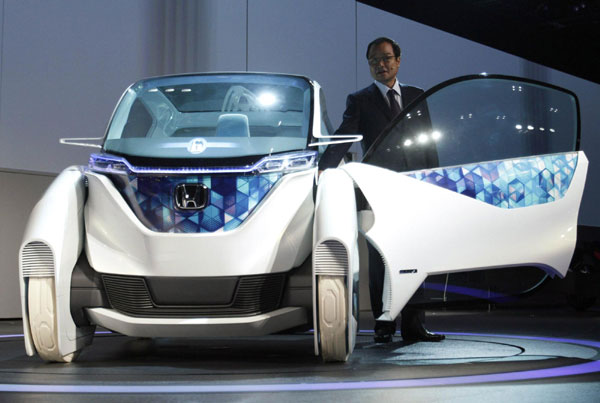 Honda Motor Company President Takanobu Ito speaks next to the company's electric Micro Commuter Concept city vehicle during a news conference at the 42nd Tokyo Motor Show in Tokyo November 30, 2011. Tokyo Motor Show kicks off