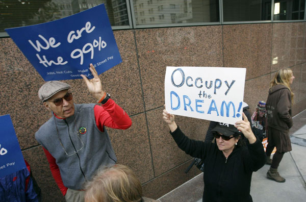 Joanne Tortorici Luna (R) holds a sign as activists with Occupy Los Angeles unite with African American faith and clergy community members to hold an 'Occupy the Dream' rally in honor of American civil rights icon Dr. Martin Luther King outside the Los Angeles Federal Reserve Bank offices on Martin Luther King Day in Los Angeles, California January 16, 2012. Martin Luther King Day marked in US